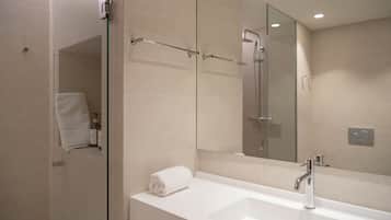 Un baño moderno con cabina de ducha de vidrio, un lavabo blanco y un espejo grande.