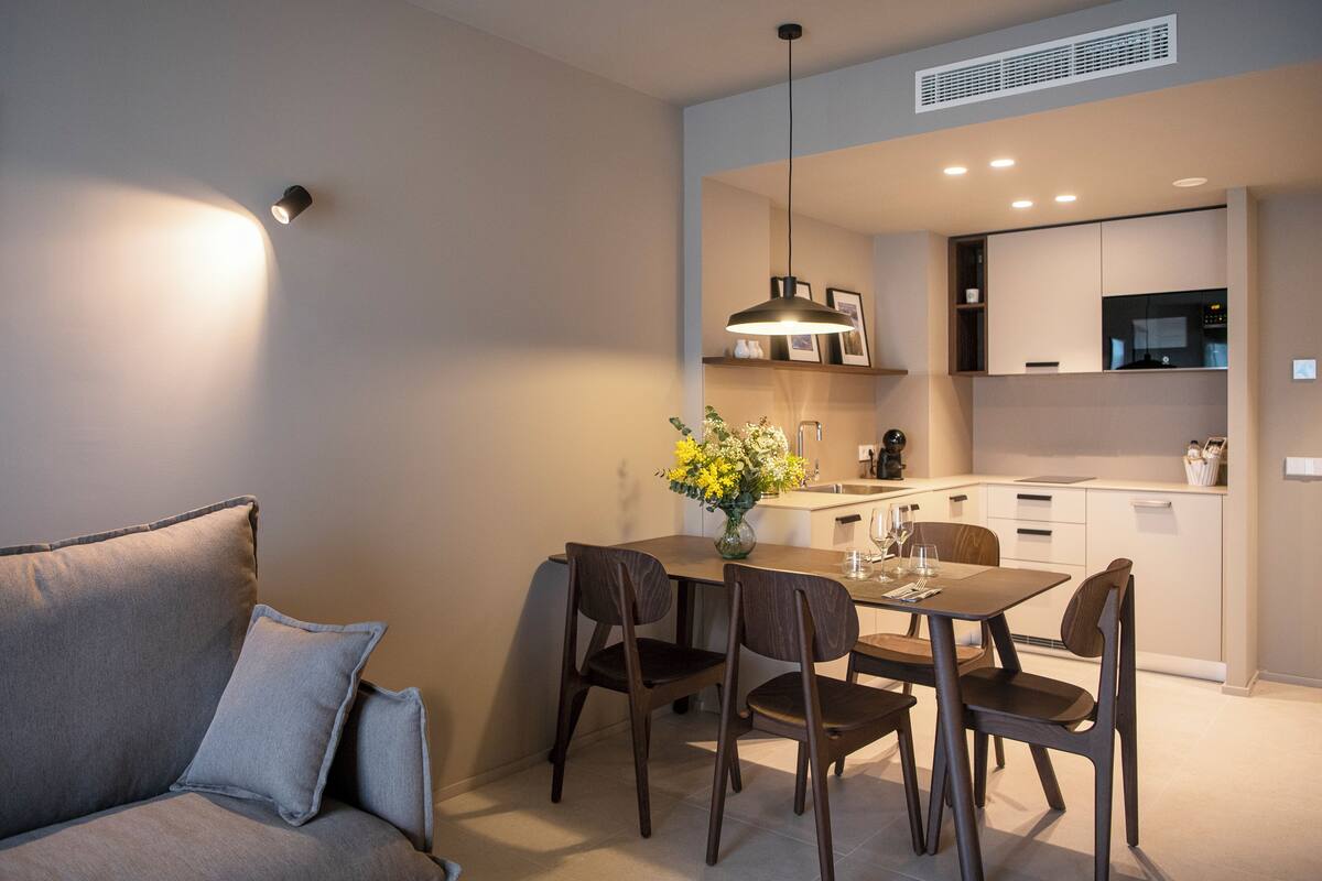 Une cuisine moderne avec un coin repas, comprenant un canapé, une table à manger, des chaises et un vase de fleurs.