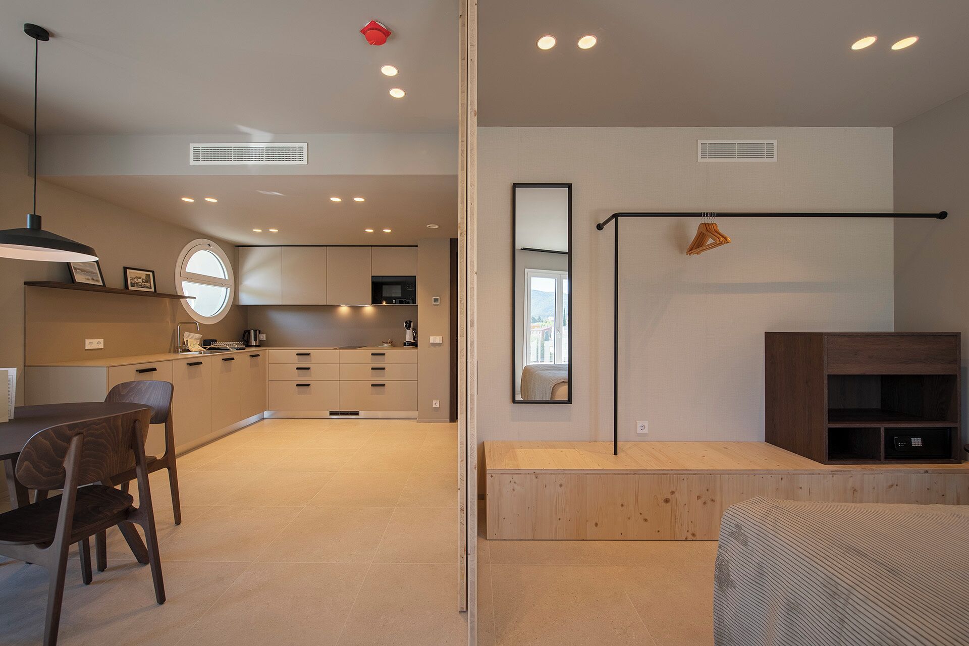 Un espacio habitable moderno y abierto con cocina, comedor y un espejo grande que refleja la habitación.