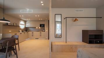 Un espacio habitable moderno y abierto con cocina, comedor y un espejo grande que refleja la habitación.