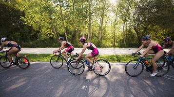 A group of cyclists riding on a paved path surrounded by trees.