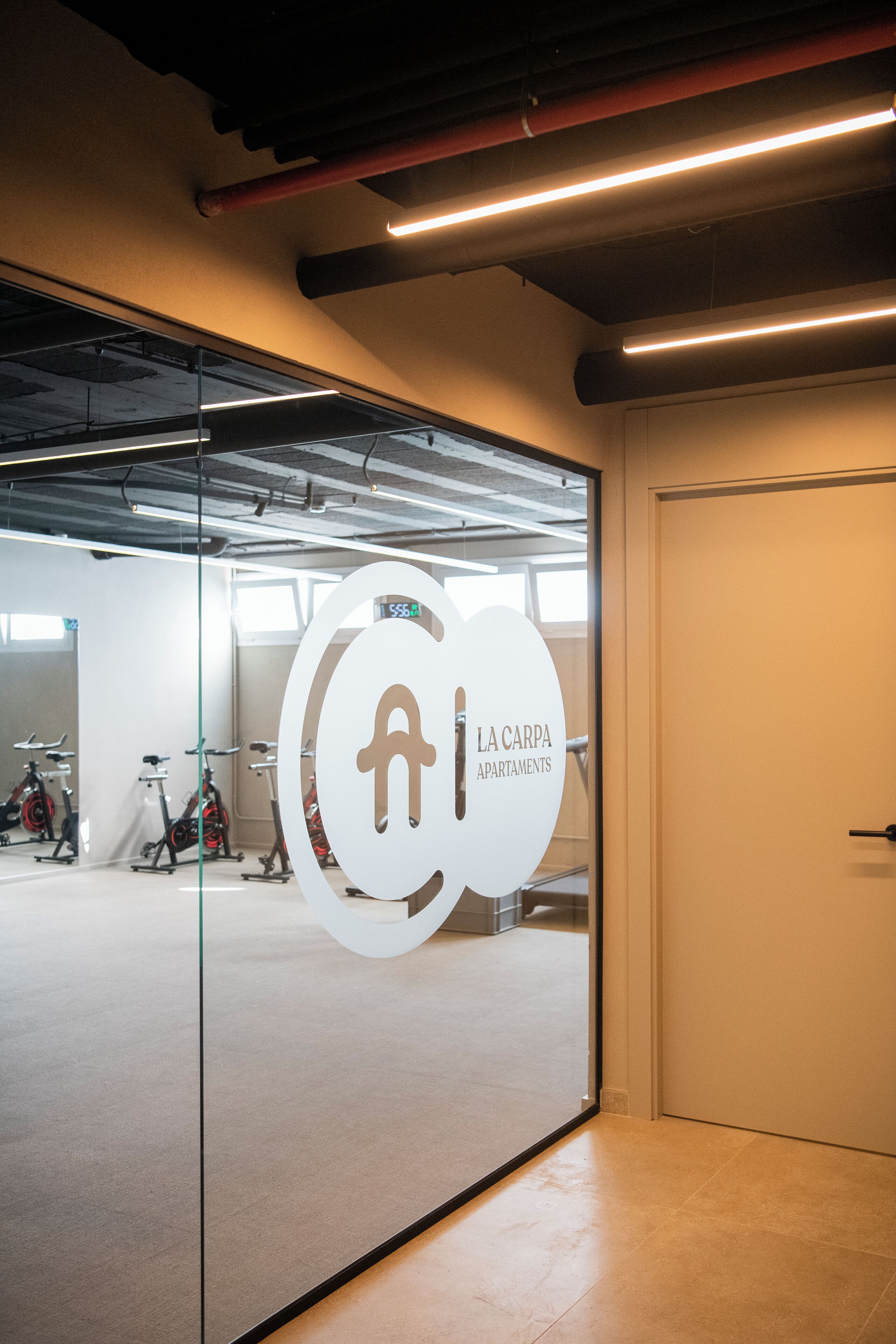 Un interior moderno con una pared de vidrio que muestra un logo y el texto "LA CARPA APARTMENTS".