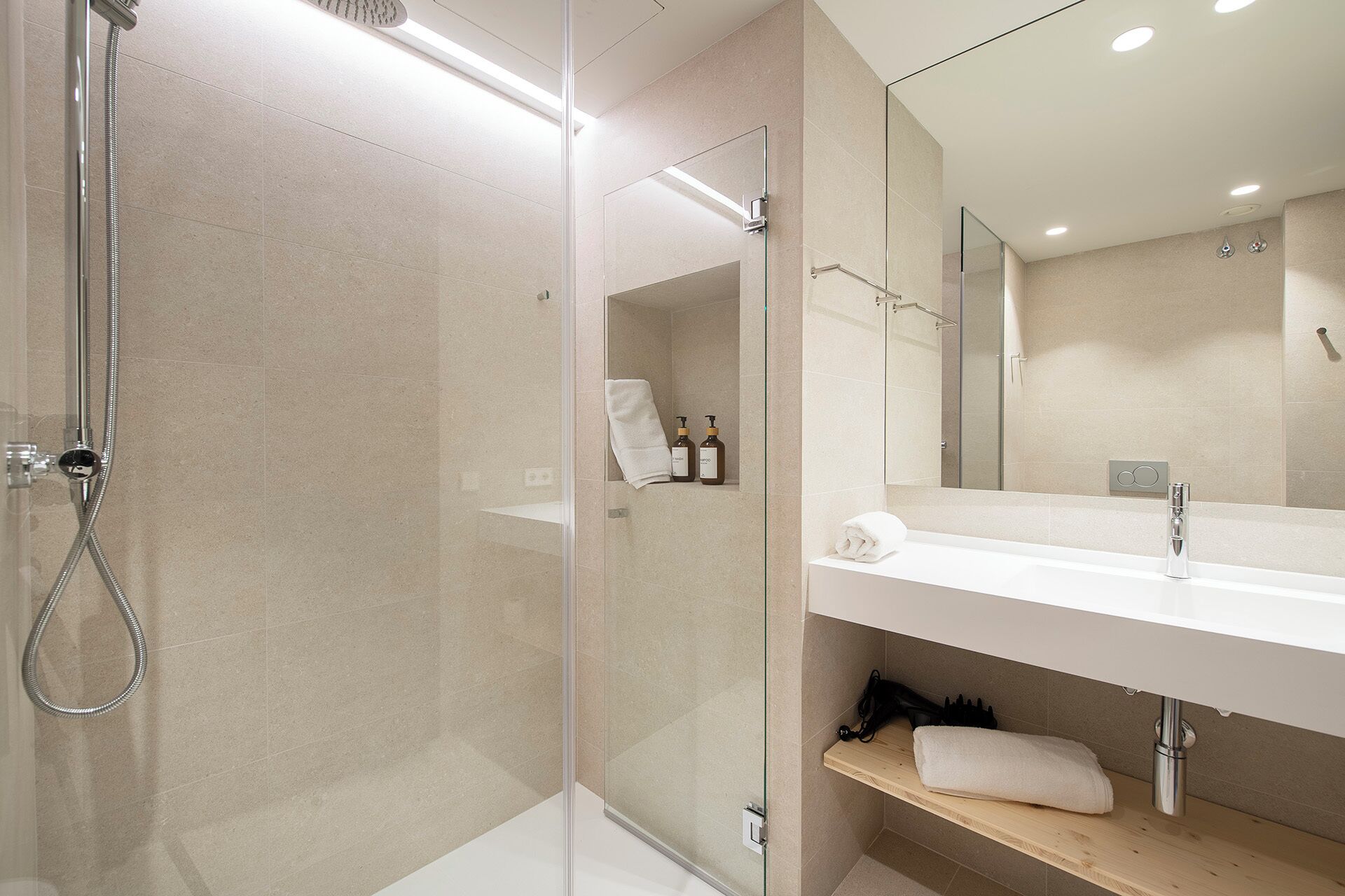 A modern bathroom with a glass shower enclosure, a white sink, and a mirror above it.