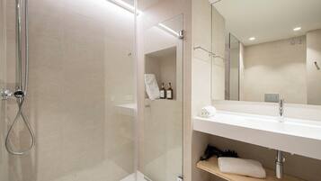A modern bathroom with a glass shower enclosure, a white sink, and a mirror above it.