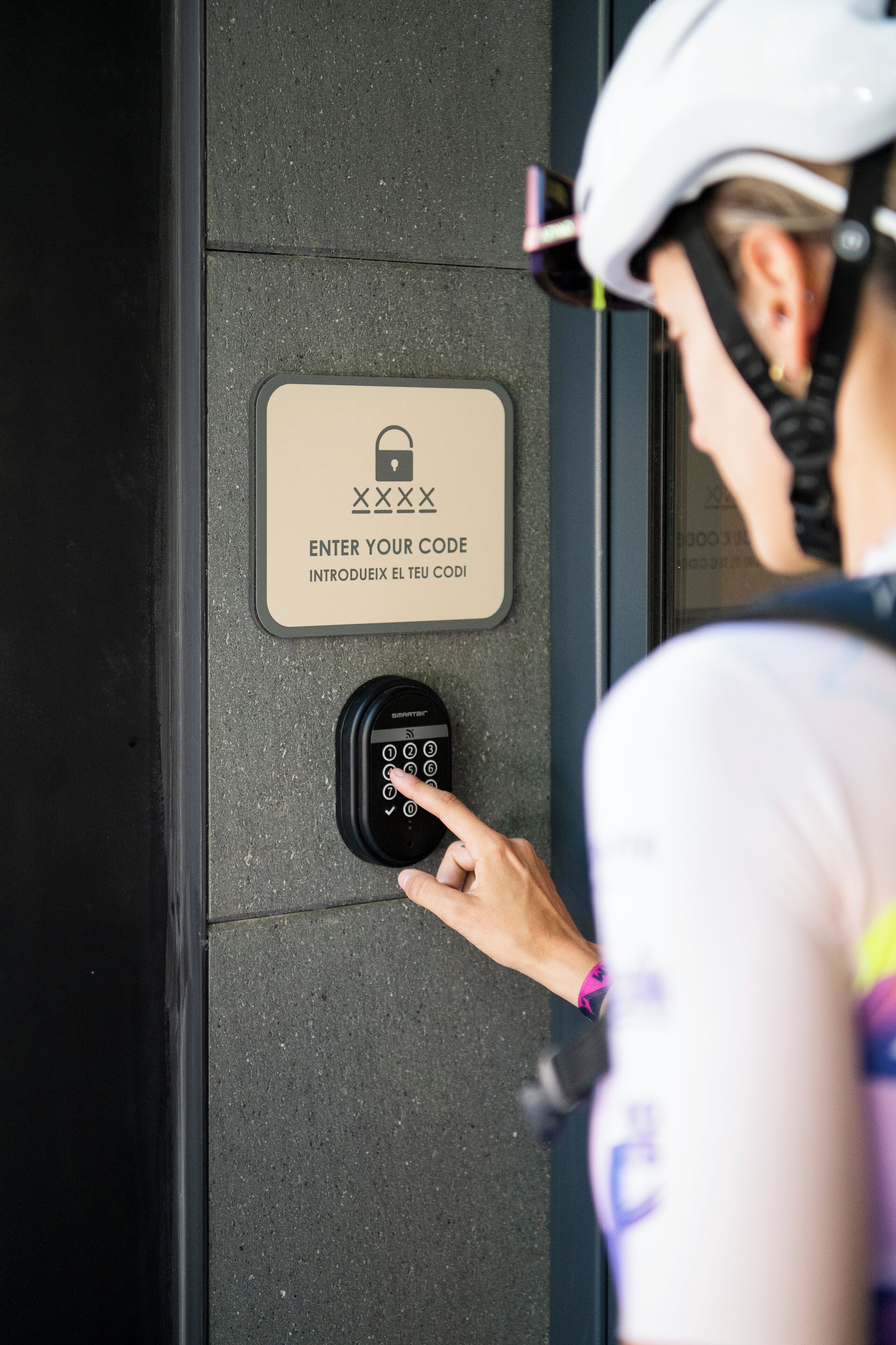 Iemand tikt een code in op een keypad naast een bord met een slotpictogram en tekst in verschillende talen.
