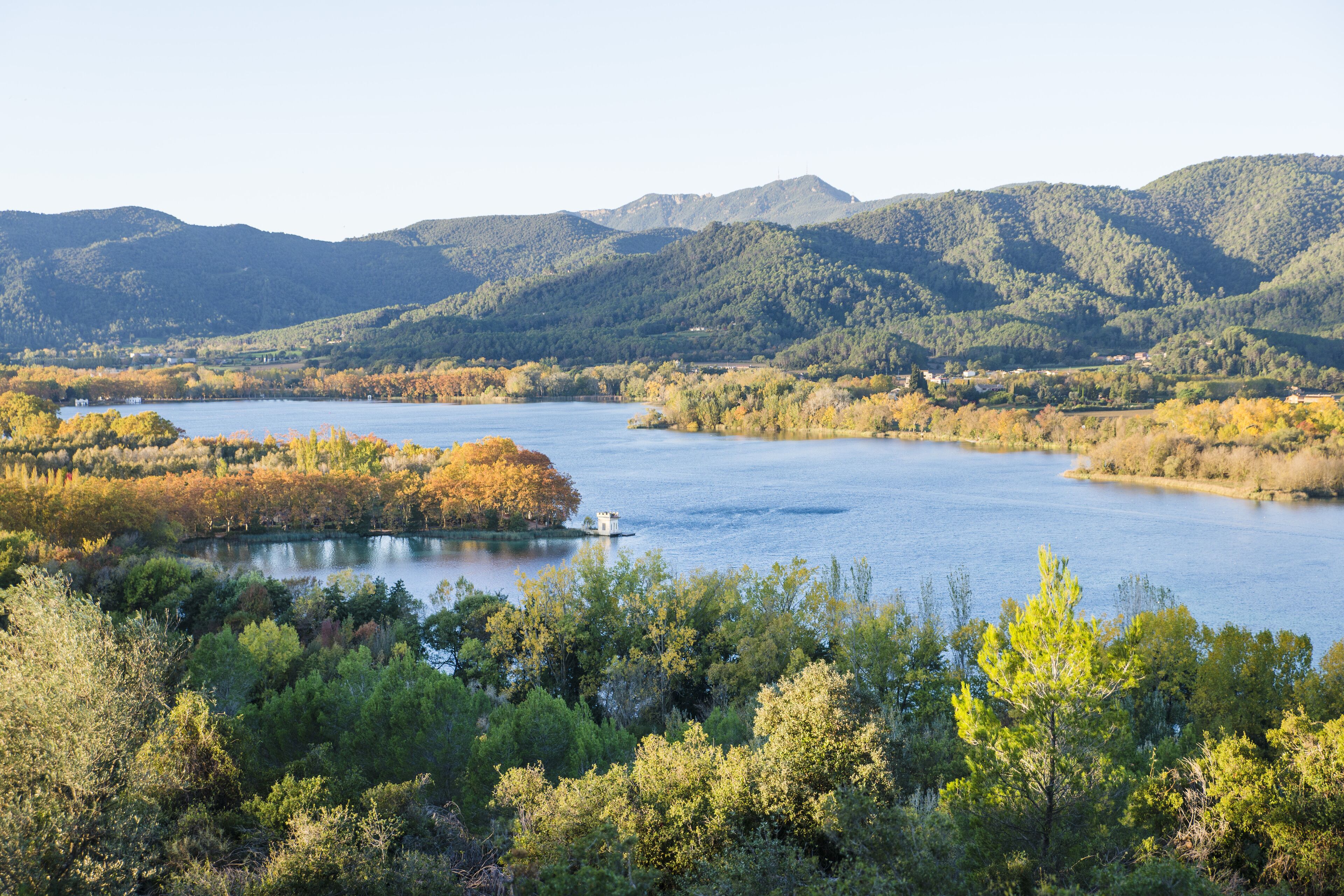 A scenic view of a lake surrounded by forested hills.