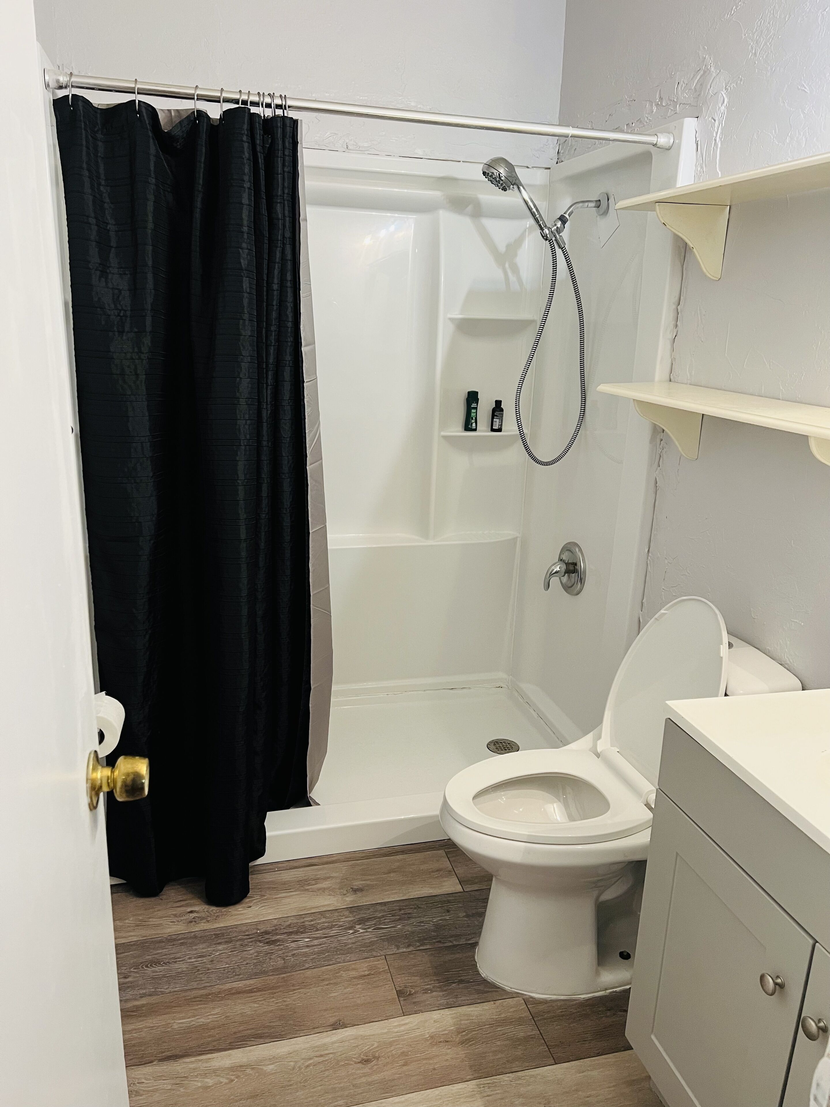Et badeværelse med bruser, toilet og håndvask.