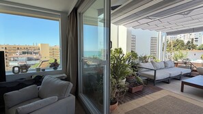 A balcony with a sofa, a table, and potted plants.