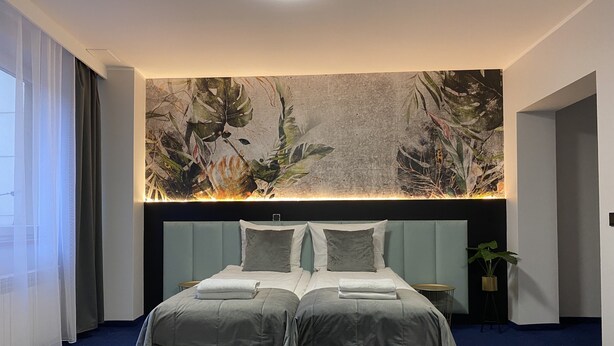 A double bed with a headboard, a large wall mural, and a blue carpet. - Cube House Aparthotel (Kraków)