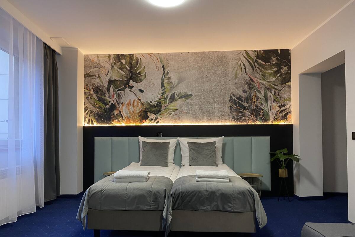 A double bed with a headboard, a large wall mural, and a blue carpet.