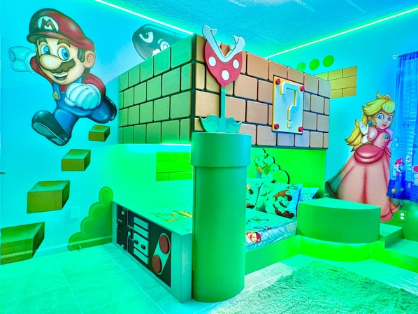 Una habitación con una cama, una pared con temática de Mario y una pared con temática de princesa.