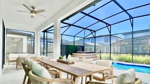 Une vaste terrasse dotée d’une piscine, de meubles en osier et offrant une vue sur les maisons voisines.