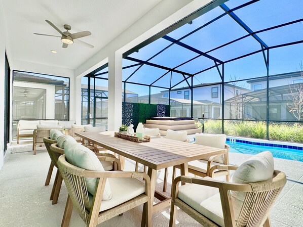 Eine geräumige Terrasse mit Pool, Korbmöbeln und Blick auf die Nachbarhäuser.