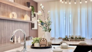 Une cuisine moderne avec un évier en acier inoxydable, un vase rempli de fleurs et un coin repas avec une table mise pour deux personnes.