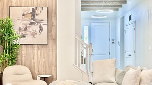 Un salon moderne avec un canapé beige, une petite table ronde et une plante en pot.