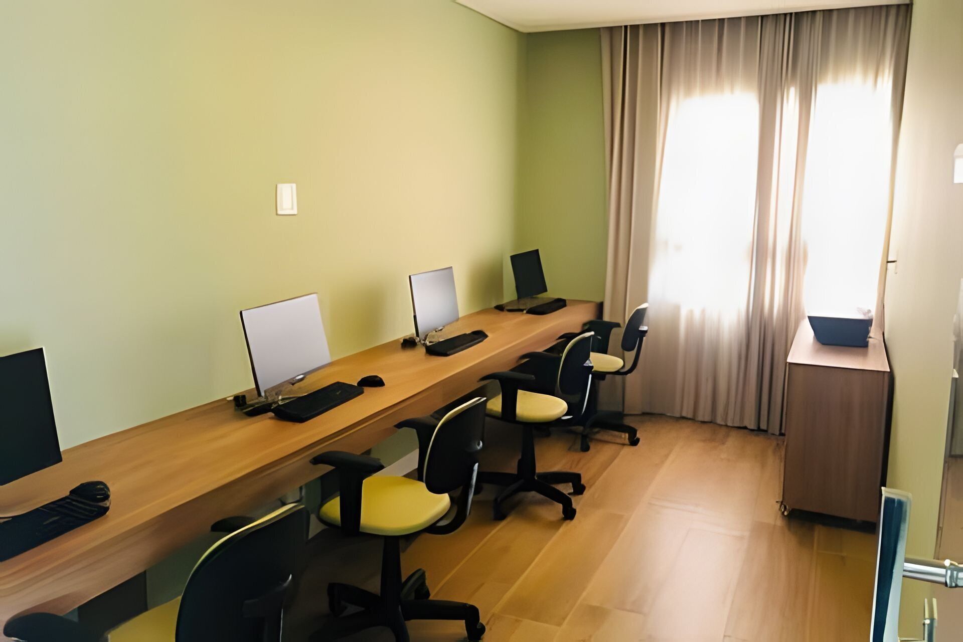 Une salle de conférence avec une longue table, de nombreuses chaises et des écrans d’ordinateur.