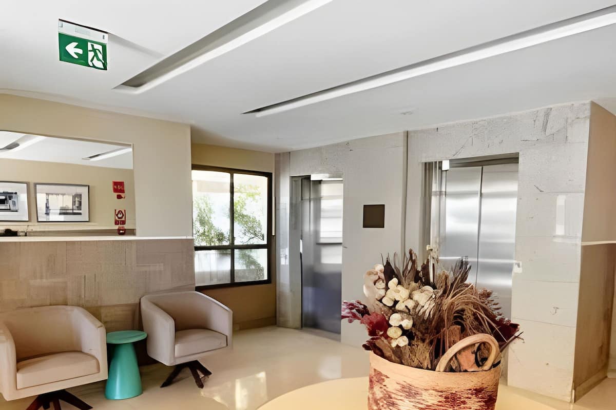 Un área de espera moderna con dos sillones, una mesita y una cesta decorativa.