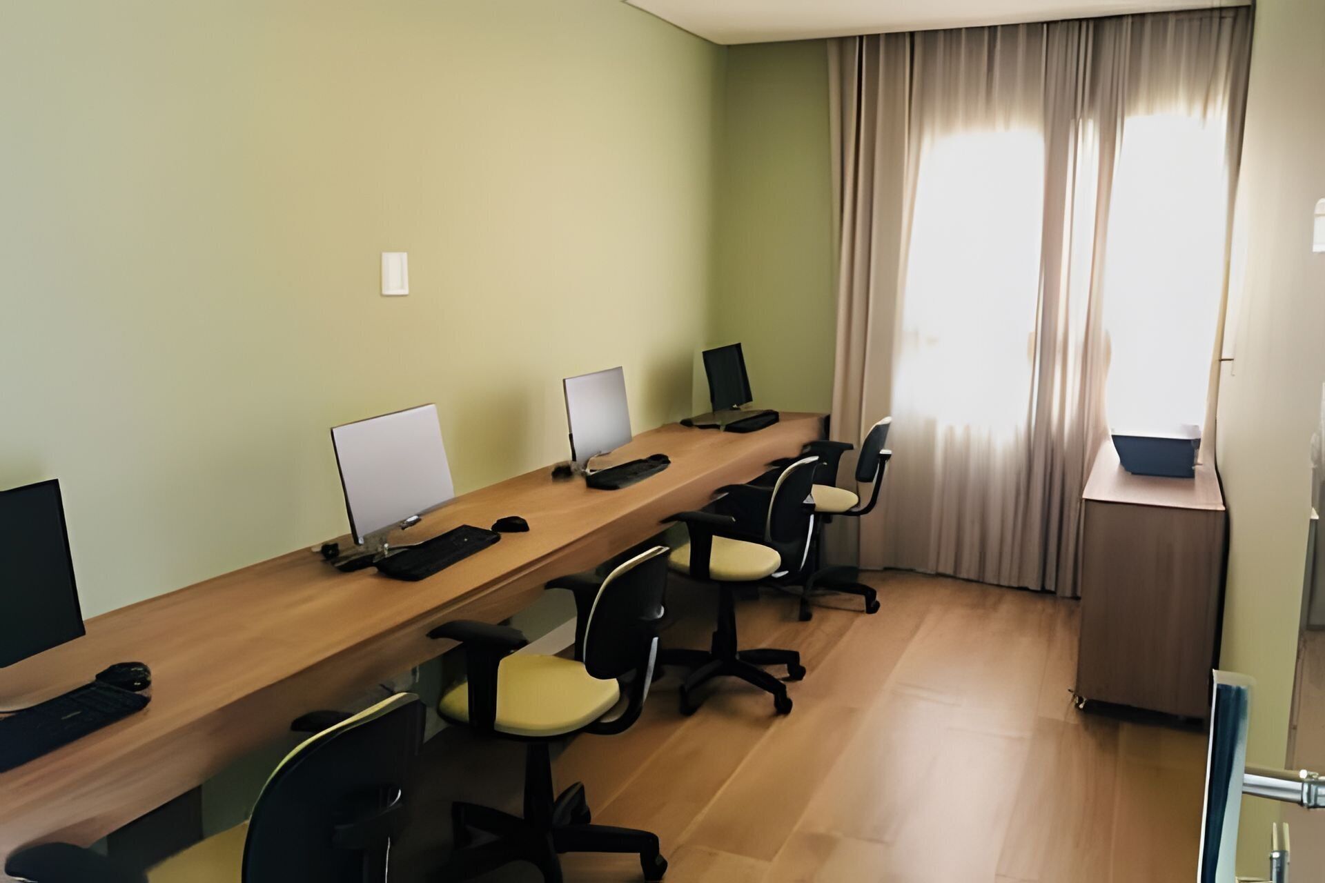 A conference room with a long table, multiple chairs, and computer monitors.