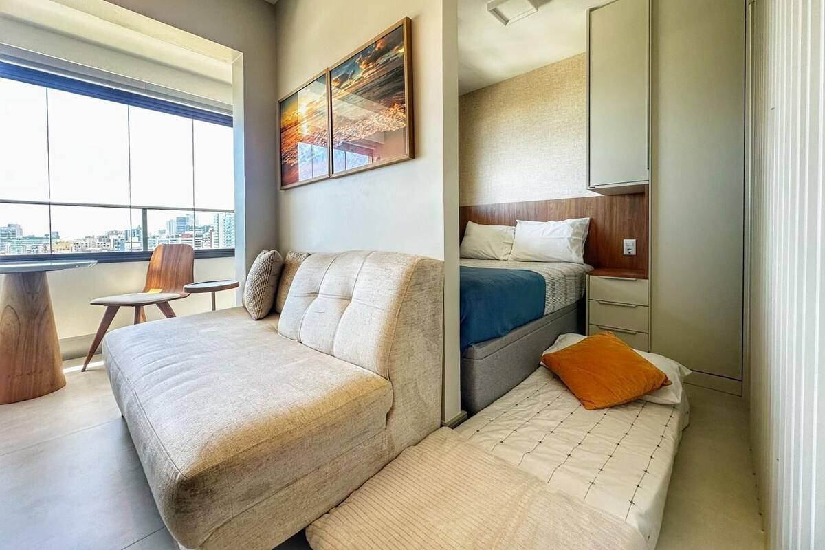 Un dormitorio moderno con sofá cama, una cama separada, un escritorio y una silla.