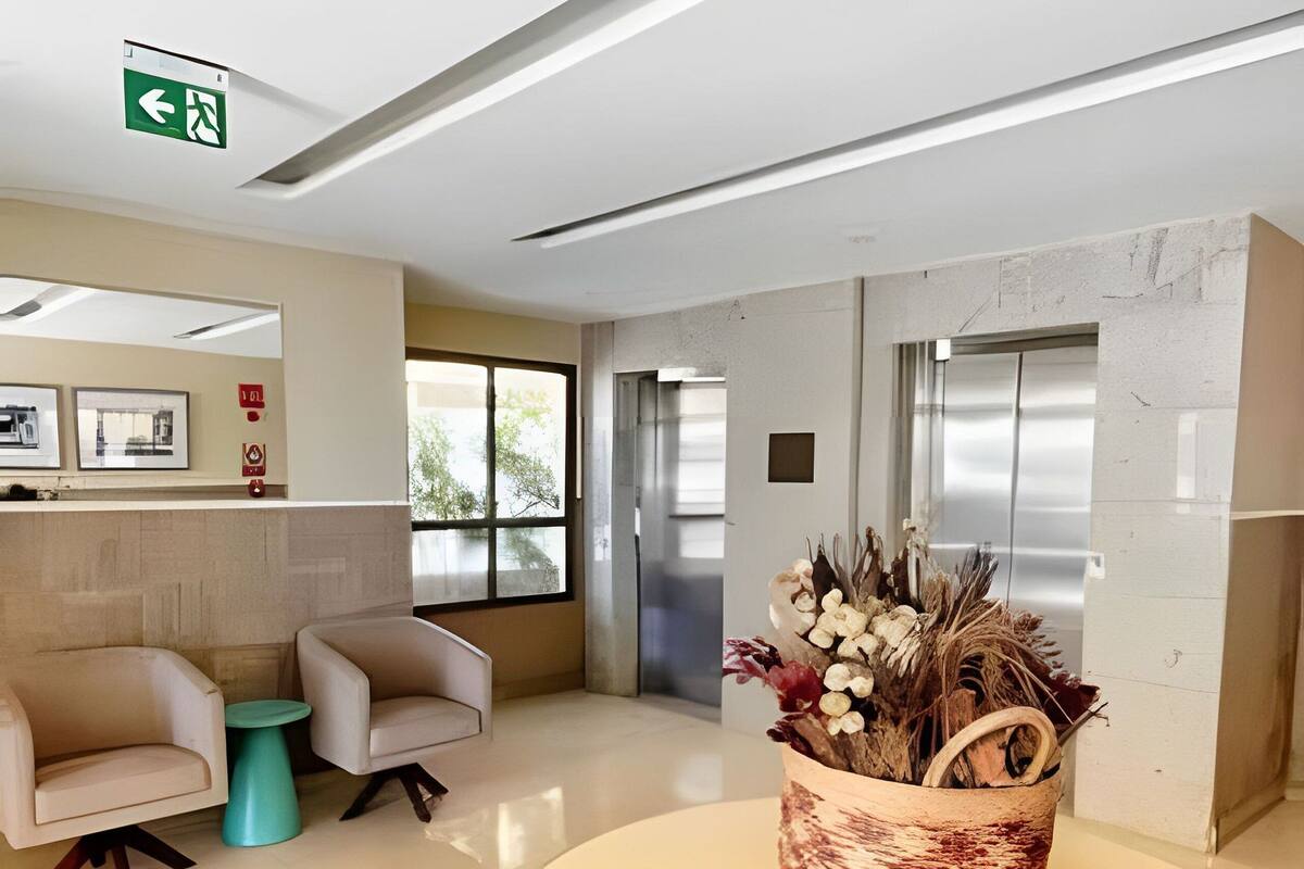 Una zona de recepción moderna con una mesa redonda, dos sillones, una mesita auxiliar verde y una cesta decorativa con elementos naturales.