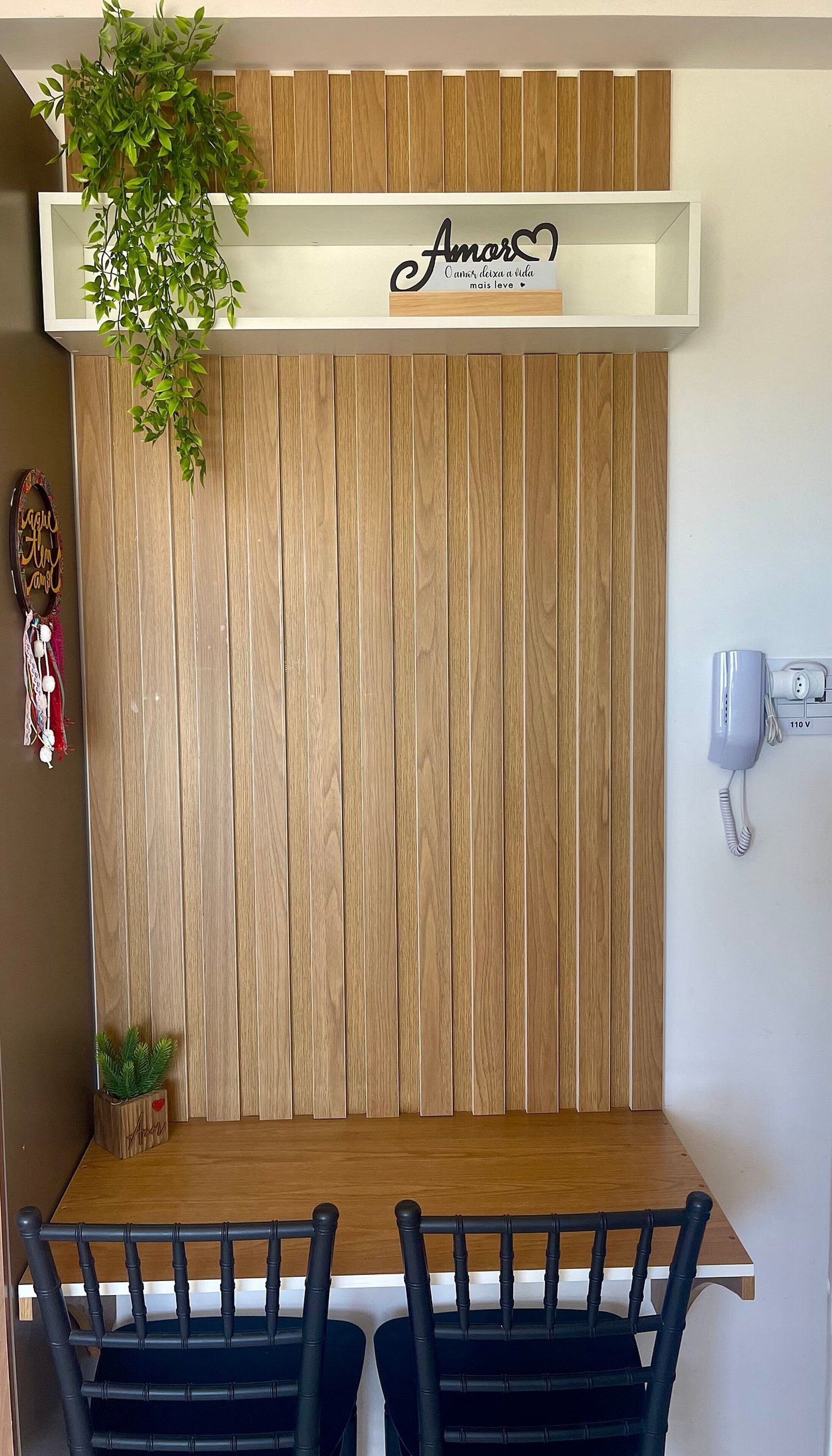 A dining area with a wooden wall, a hanging plant, and a mounted phone.