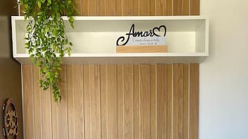 A dining area with a wooden wall, a hanging plant, and a mounted phone.
