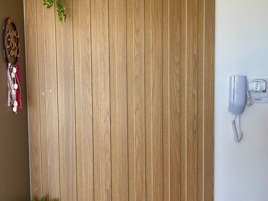 A dining area with a wooden wall, a hanging plant, and a mounted phone.