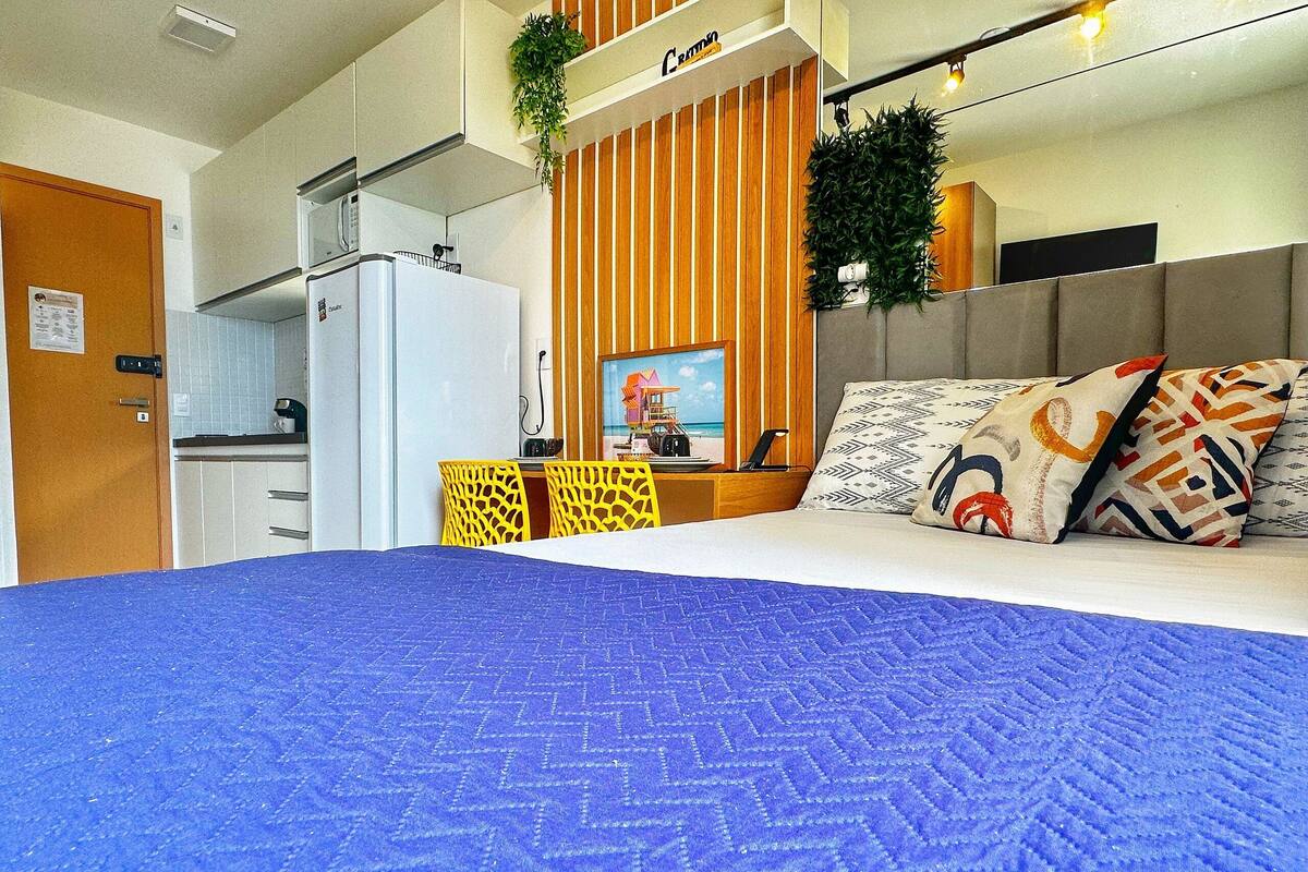 Habitación de hotel con cama, escritorio, kitchenette y baño.