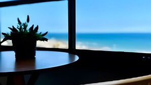 Una mesa con una planta en maceta y vista al océano a través de amplios ventanales.