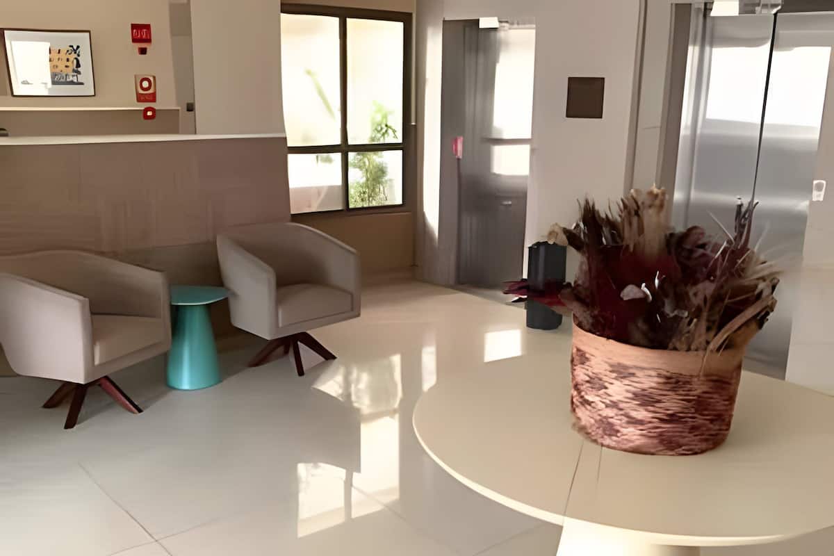 Un vestíbulo moderno con una mesa redonda, dos sillones, una planta en maceta y un amplio ventanal.