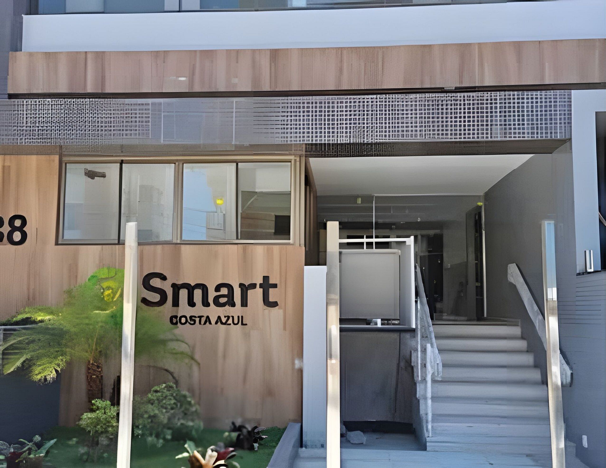 A modern building entrance with a wooden facade, a staircase, and a sign reading "Smart Costa Azul."