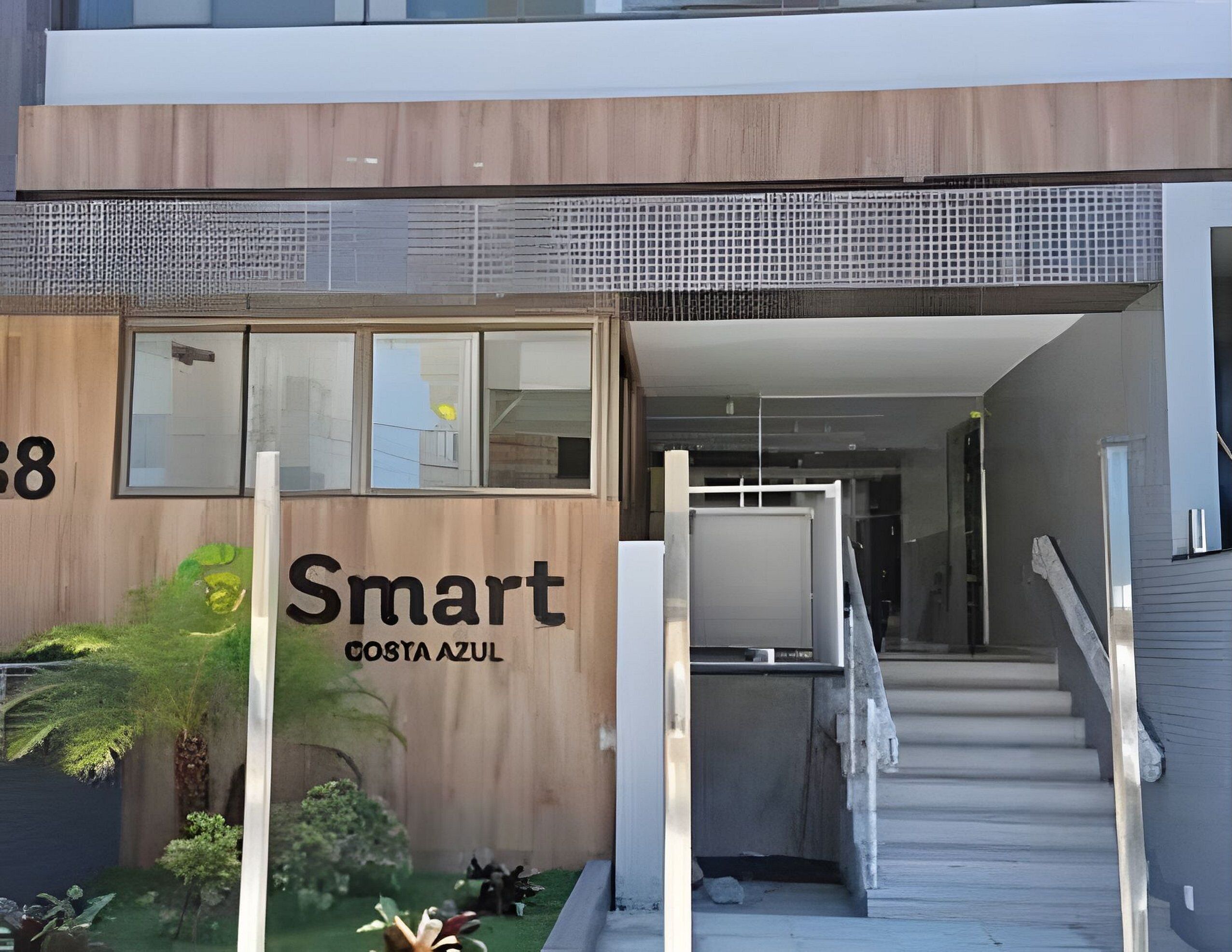 Ein moderner Gebäudeeingang mit Holzfassade, einer Treppe und einem Schild mit der Aufschrift 'Smart Costa Azul'.