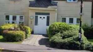 A two-story residential building with a symmetrical facade, a central entrance with a door, and a small front garden. - The Pennington Apartment Leigh (Leigh)