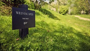 Ein Schild mit der Aufschrift 'WILD ESCAPES THIS WAY' und einem Finger, der in eine Richtung zeigt.