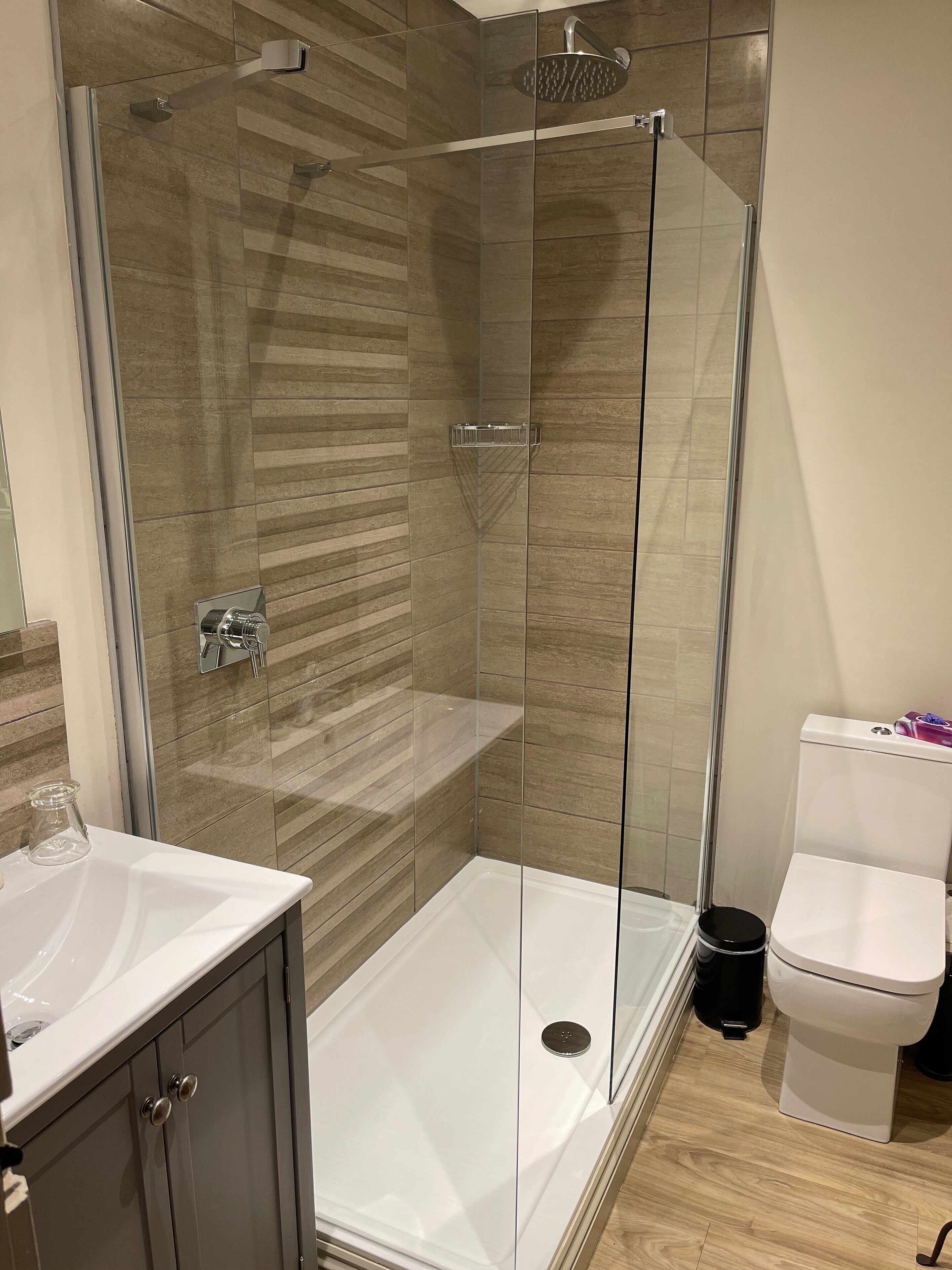Un baño moderno con cabina de ducha de vidrio, un lavamanos blanco y un inodoro.