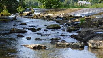 Un río con rocas y una casa al fondo.