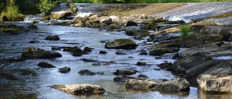 A river with rocks and a house in the background.