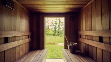 A sauna room with wooden benches and a bucket of water.