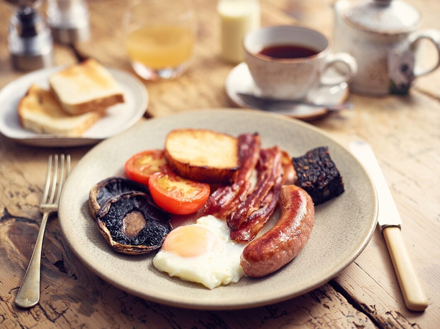 A breakfast plate with eggs, bacon, tomatoes, mushrooms, and toast.