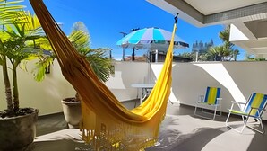 Un'amaca su un balcone con piante in vaso, un tavolo e delle sedie.