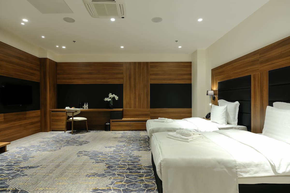 A modern hotel room with a large bed, a desk, and a vanity.