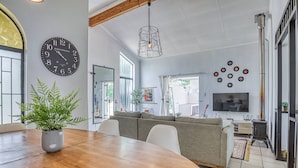 Un salon moderne avec une table à manger en bois, un canapé, une grande horloge et un téléviseur.