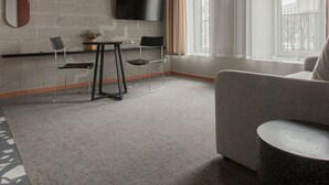 A modern living room with a grey brick wall, a flat-screen TV, a grey sofa, and a round coffee table.