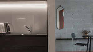 A modern kitchen with a built-in sink, a kettle, and a mirror on the wall.