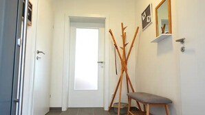 A hallway with a white door, a wooden bench, and a mirror on the wall. - Charming semi-detached house in idyllic Stainz (Steiermark)