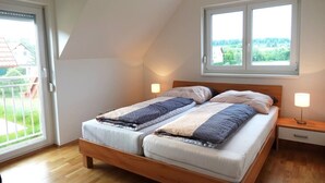 A bedroom with two beds, a window with a view, and a balcony. - Charming semi-detached house in idyllic Stainz (Steiermark)