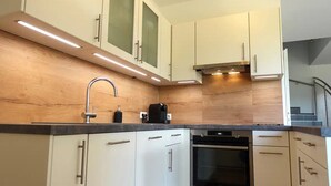 A modern kitchen with white cabinets, a stainless steel oven, and a wooden countertop. - Charming semi-detached house in idyllic Stainz (Steiermark)