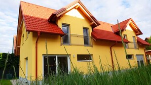A yellow two-story house with a red roof, a balcony, and a door. - Charming semi-detached house in idyllic Stainz (Steiermark)