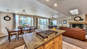 A spacious kitchen with granite countertops, a dining area with wooden chairs, a fireplace, and a leather sofa. - 1759 Venice Drive 5 Bedroom Home by RedAwning (South Lake Tahoe)