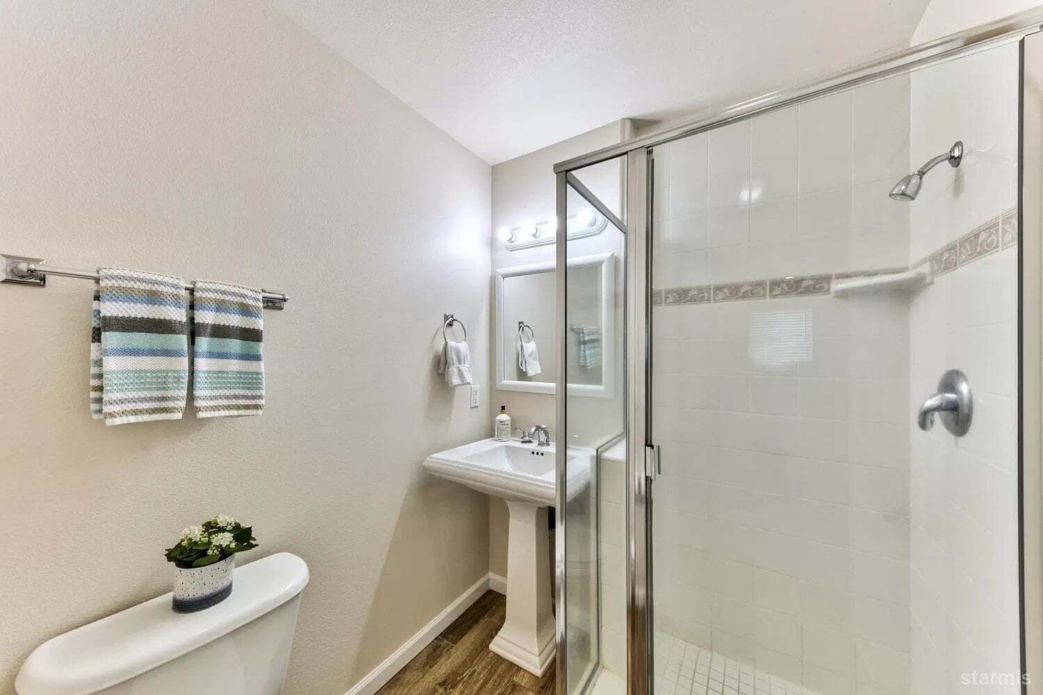 Et badeværelse med toilet, vask og brusekabine med glasvægge.